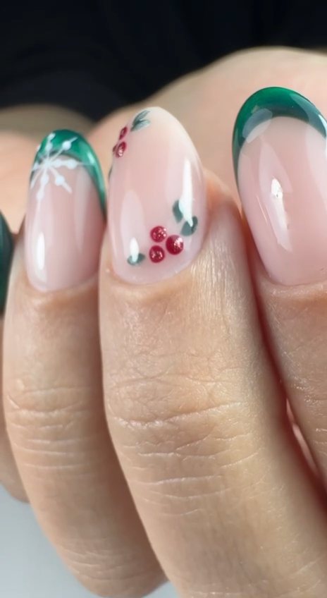 Sheer nude gel nails with emerald green French tips, hand-painted holly berries and a snowflake at Paradisse Studio, Richmond Hill