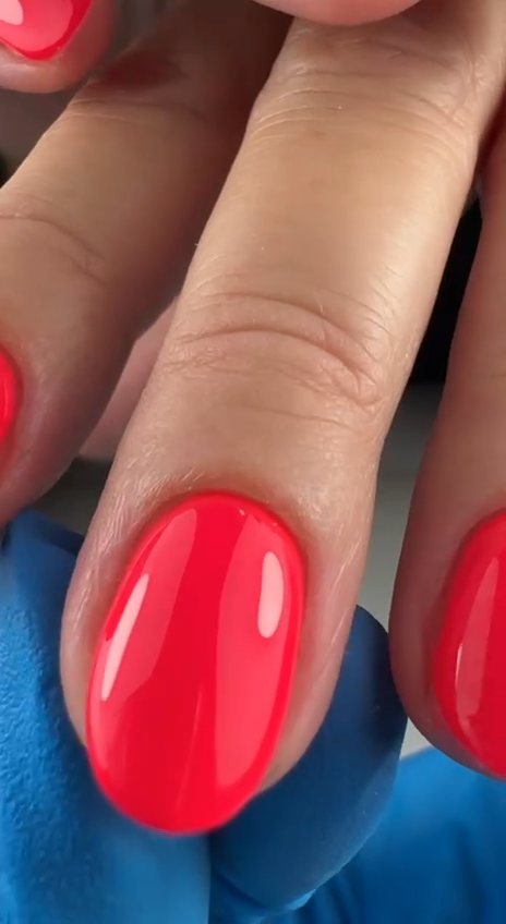 Close-up of a glossy coral red gel manicure on round nails at Paradisse Studio, Richmond Hill