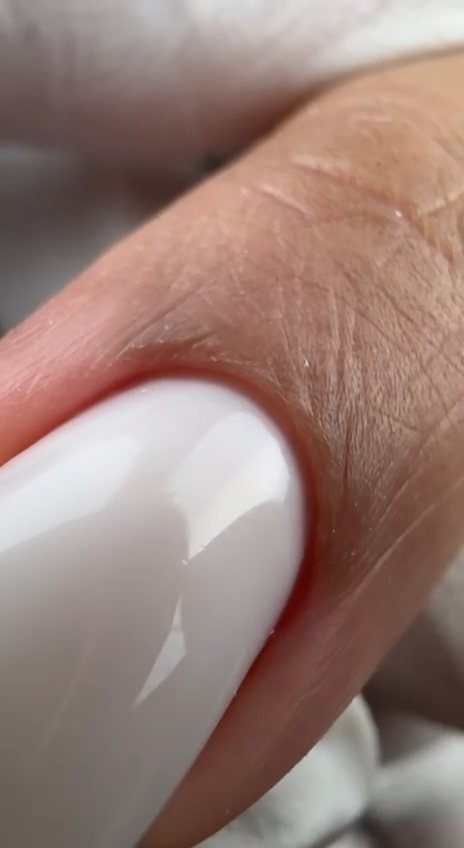 Close-up of a glossy milky white gel nail with a clean cuticle line after a Russian manicure at Paradisse Studio, Richmond Hill