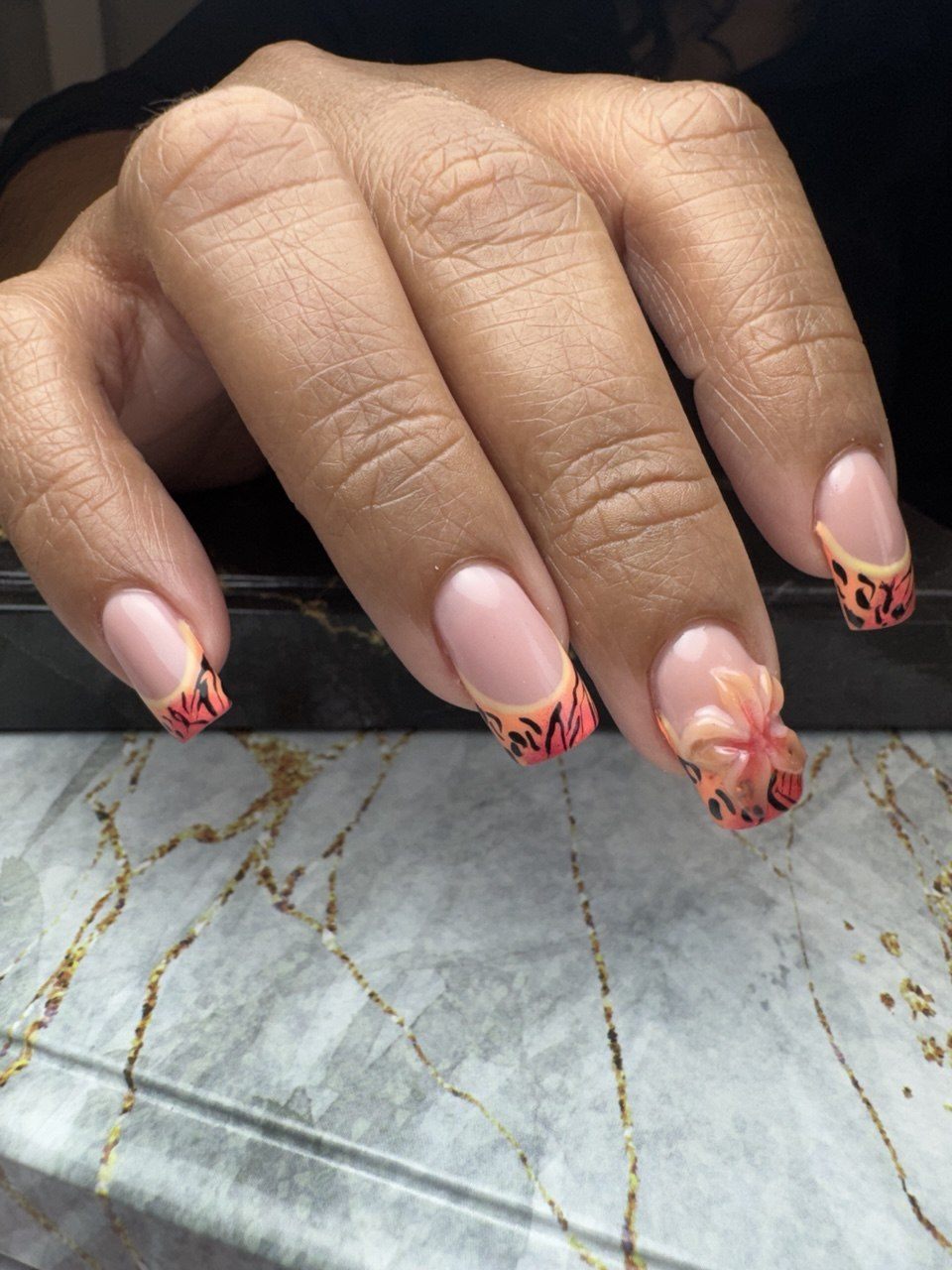 Square gel nails with coral and orange ombre French tips, black animal-print strokes and a 3D flower accent at Paradisse Studio, Richmond Hill